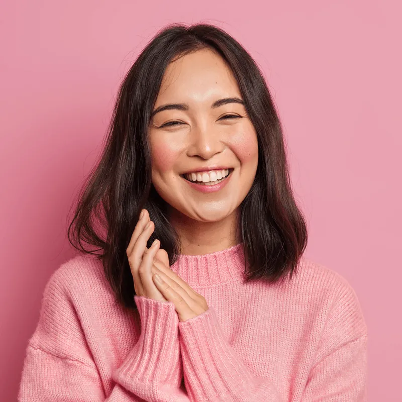 Woman in a cozy pink sweater smiling, symbolizing handmade preparation with care